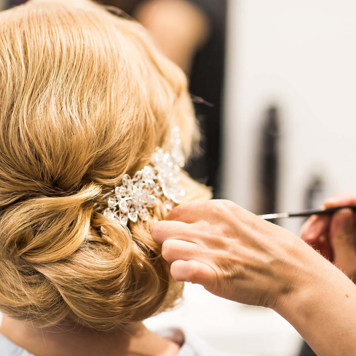 Hair stylist makes the bride before the wedding